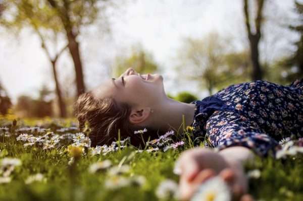 woman lying in flowers happy - استرس را چگونه کنترل کنیم؟