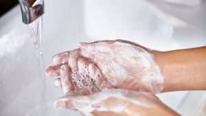 handwashing feature 300x169 - Woman washing her hands at the kitchen sink.