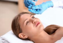 دختر جوانی که دراز کشیده و پزشک بوتاکس را به پیشانی او تزریق می کند