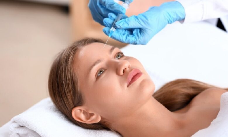 دختر جوانی که دراز کشیده و پزشک بوتاکس را به پیشانی او تزریق می کند